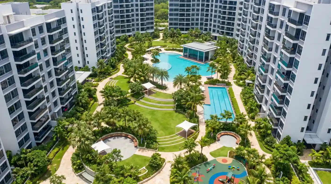 Aerial view of modern apartment towers surrounding a landscaped central garden with swimming pools and walkways
