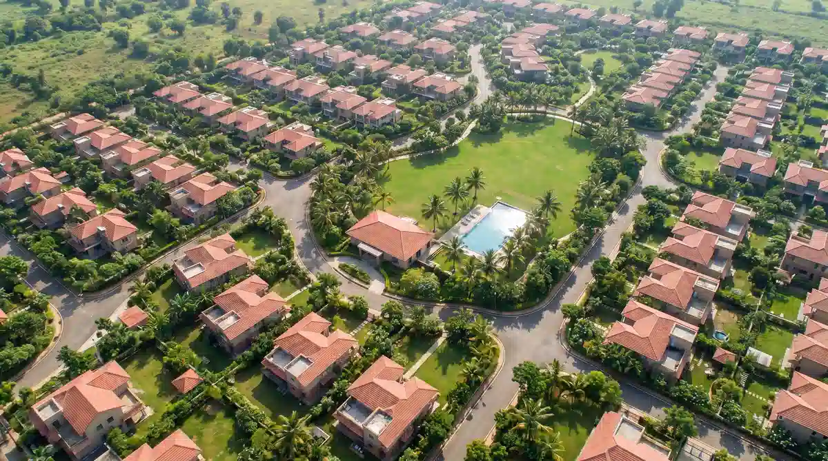 Aerial view of luxury villa community with tree-lined roads, private gardens, and clubhouse greens